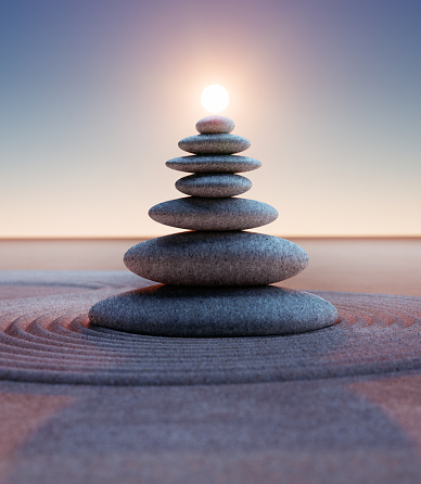 Stack of pebbles with spiral sand waves and sun