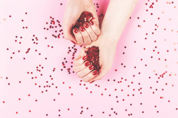 istock Two woman hands and falling confetti on pink background. 1264090747