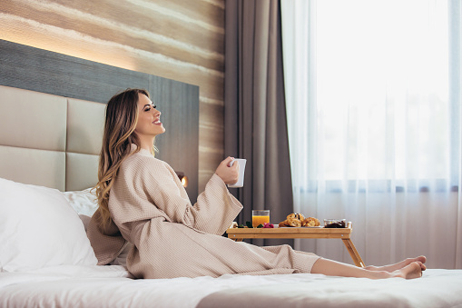 Relaxed Woman Having Breakfast in Bed, home or hotel room