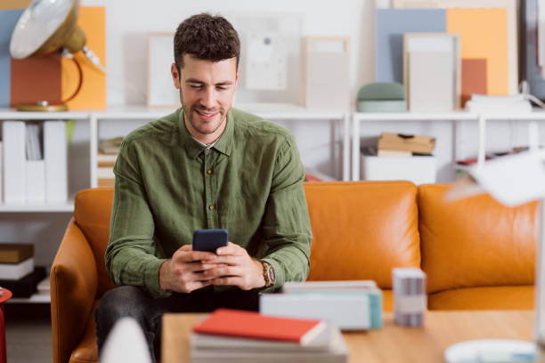 istock Smiling Modern Businessman Sitting in the Office and Using his Smartphone to Communicate Online 1264090898