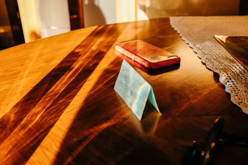 Phone and sticky note on the table in the sunlight