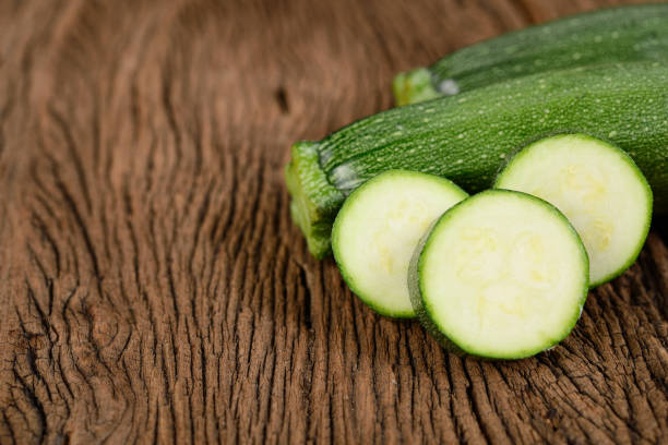 istock uncooked whole and sliced fresh zucchini on wooden background 1264092800