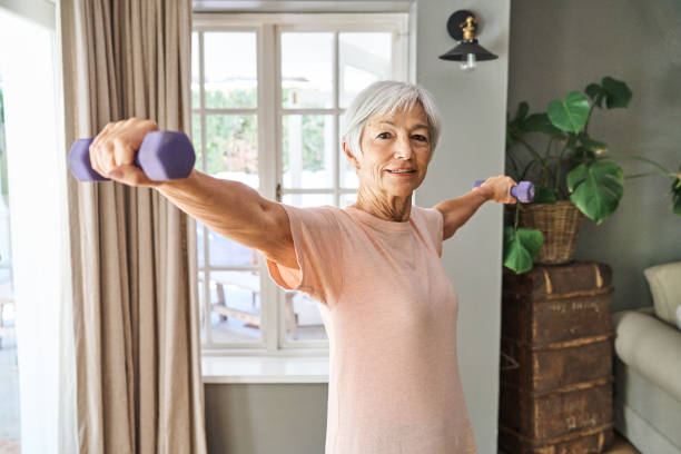 istock Smiling senior woman exercising with weights at home 1264092856