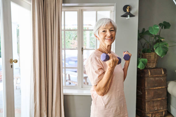 istock Smiling senior woman lifting dumbbells while working out at home 1264093587
