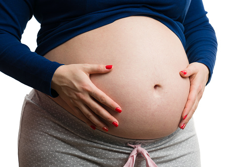 Pregnant woman and her growing belly isolated on a black background
