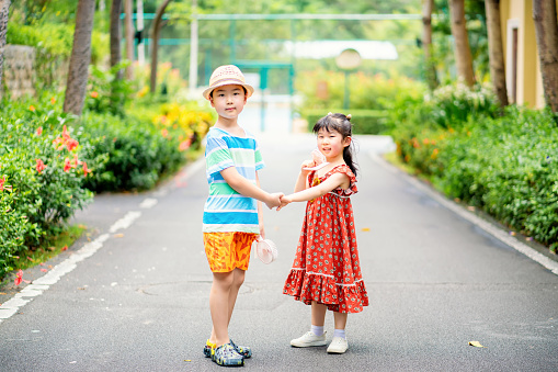 Two Asian children walking through the path