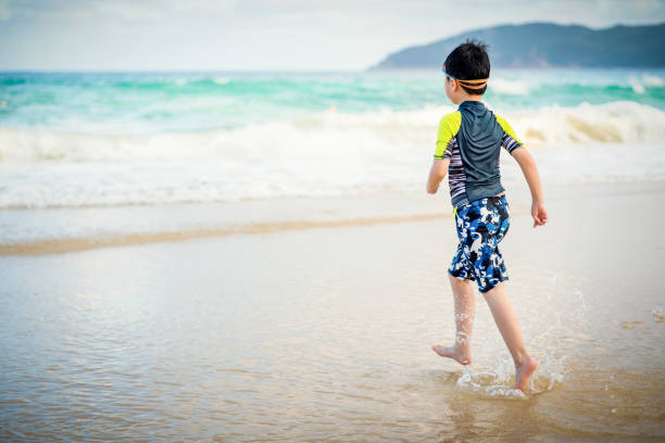 istock Little boy playing and splashing in sea waves 1264096536