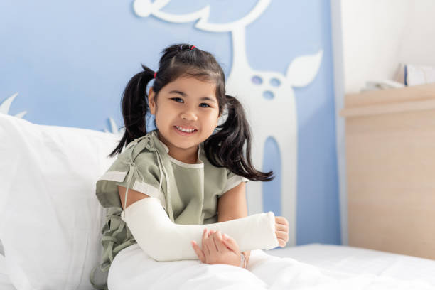 Asian girl treatment in hospital lying on the bed hurting with broken arm back from surgery. Asian girl treatment in hospital lying on the bed hurting with broken arm back from surgery. orthopedic cast stock pictures, royalty-free photos & images