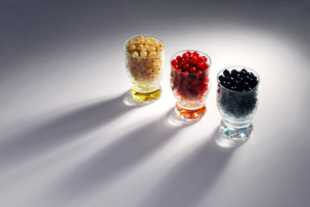 Red, black and white currants in glass in backlight with shadows. Delicious and healthy food from nature. Beautiful background with copy space