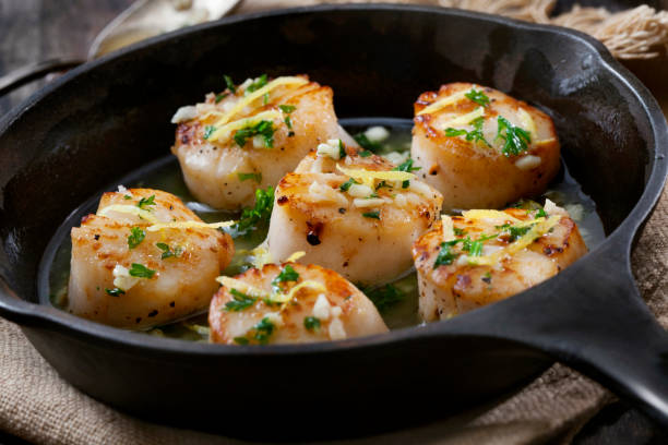 Scallops Poached in a Butter and Garlic Sauce Scallops Poached in a Garlic Butter Sauce with Parsley and Lemon Zest appetizer plate stock pictures, royalty-free photos & images
