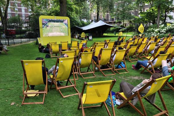 Wimbledon TV broadcast People enjoy public Wimbledon tennis tournament broadcast in Grosvenor Square park of London, UK. wimbledon seats stock pictures, royalty-free photos & images