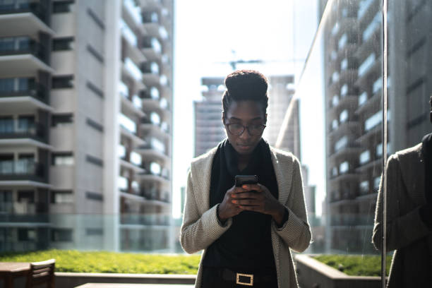 istock Young businesswoman using mobile phone and walking at office rooftop 1264108966