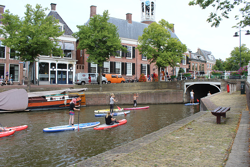 Dokkum, Netherlands, 22 July 2020: Tourists exploring the waterways of Dokkum by SUP (stand up Paddle board). The historic town of Dokkum is a popular tourist destination in Friesland.
