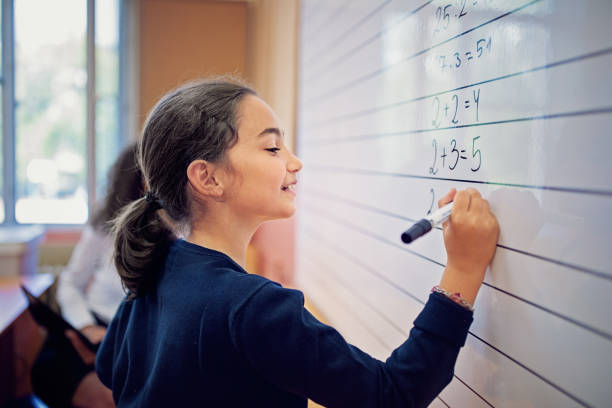 istock School girl is writing on a board in the classroom 1264110667