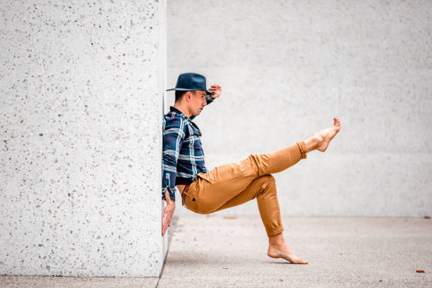 Adult man with a hat posing by the concrete wall