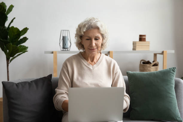 istock Elderly woman chatting in social network using laptop at home 1264113460