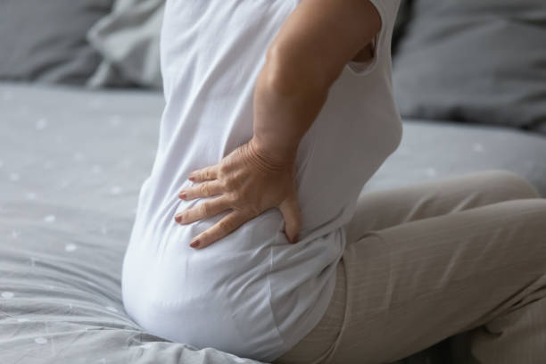 腰椎で手をつないで高齢の女性は、重度の背中痛のクローズアップを感じる - arthritis osteoporosis pain backache ストックフォトと画像
