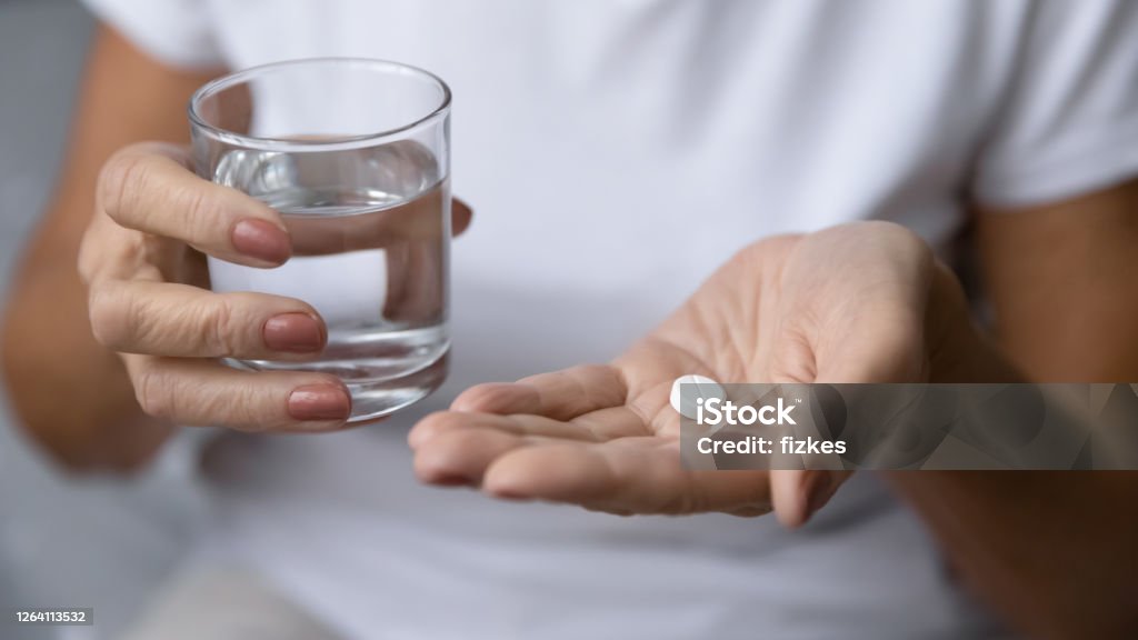 Closeup mature woman hands holding pill and glass of water Close up mature woman hands hold pill and glass of natural clean water. Older generation female take analgetic painkiller drug. Painful old age, caring for health of senior citizen, daily meds concept Senior Adult Stock Photo