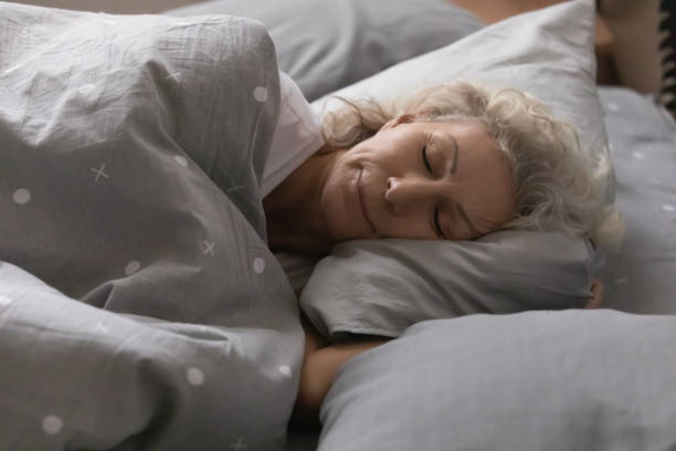istock Elderly woman sleeping under blanket in cozy bedroom 1264113546