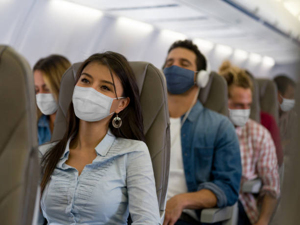 frau, die mit dem flugzeug mit einer gesichtsmaske unterwegs ist - protecting mask stock-fotos und bilder