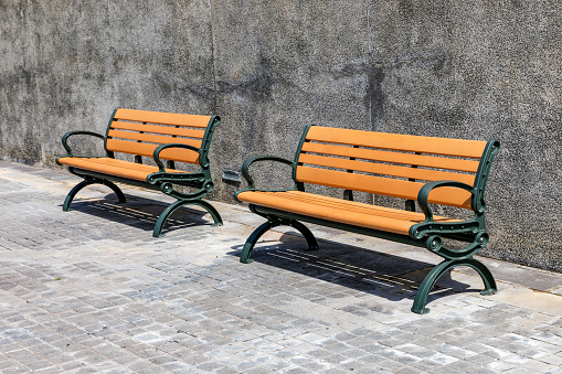 There are long iron benches on the pedestrian walkway.