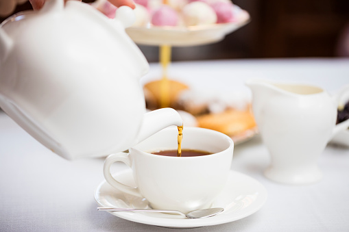 Pouring hot English tea into white ceramic tea cup