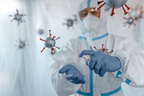 istock Man in protective suit spraying sanitizer on hand amidst covid-19 molecules 1264121579