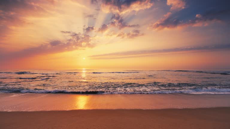 Tropical sea sunrise. Burning sky and shining golden waves splashing on the beach