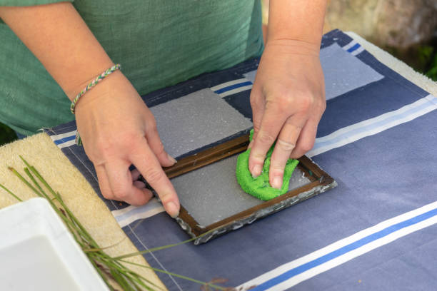 istock Woman holding frame for making paper sheets from waste paper pulp. Selective focus. Decorative and applied art. Recycling concept, ecology. 1264124569