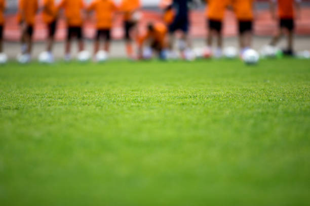 fotbalové tréninkové hřiště. fotbalisté stojící ve frontě na tréninkovém hřišti. rozmazané fotbalisty s míčky. sportovní horizontální pozadí - klubový-fotbal - stock snímky, obrázky a fotky