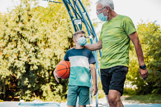 istock Boy and his grandfather playing basket during epidemic 1264127374