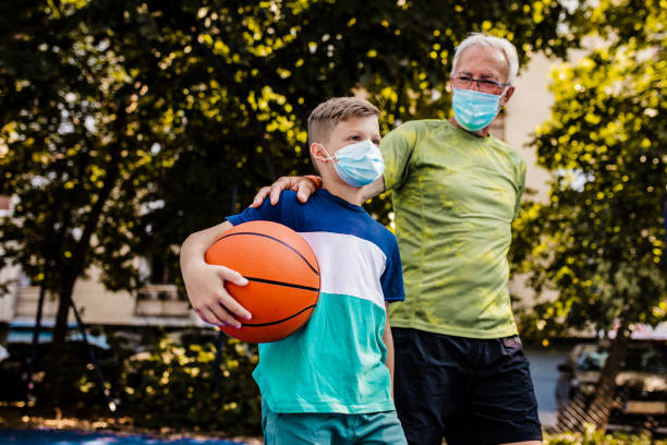 istock Boy and his grandfather playing basket during epidemic 1264127745