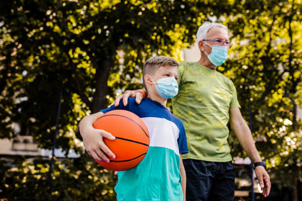 istock Boy and his grandfather playing basket during epidemic 1264127767