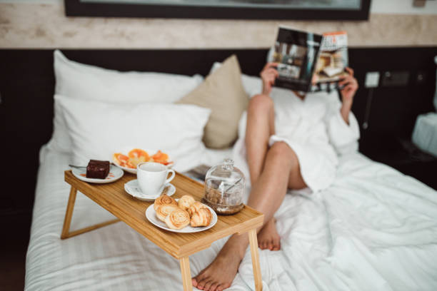 istock Woman eating breakfast in bed and reading a magazine 1264127790