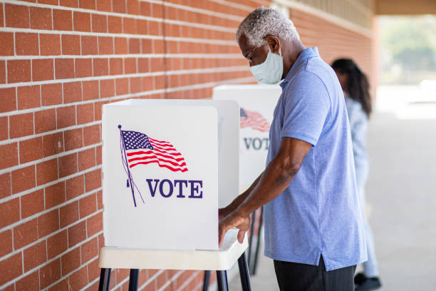 senior black man voting mit einer maske - 2020 fotos stock-fotos und bilder