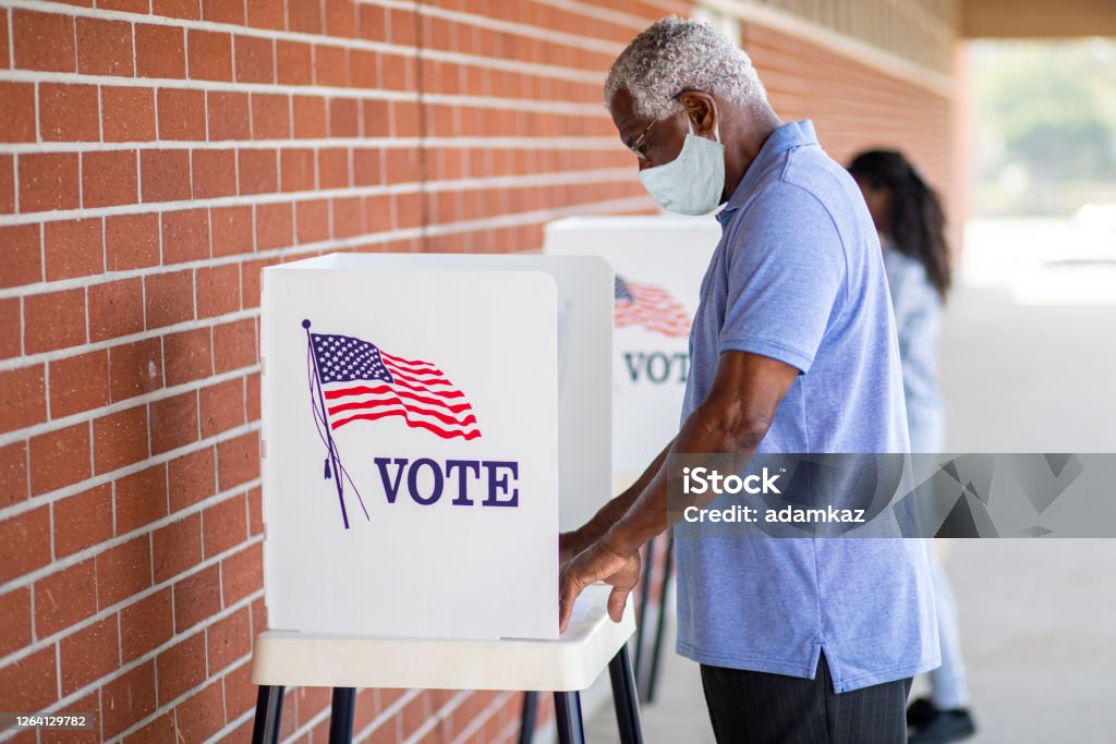 Senior Black Man Voting with a Mask A senior black man casts his ballot on election day. Voting Stock Photo