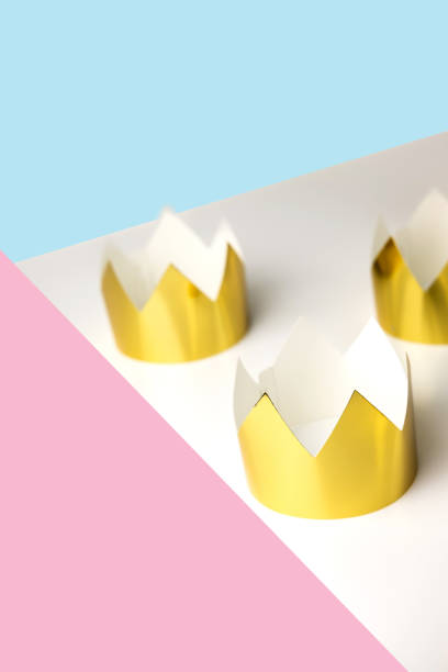 istock Cardboard golden crowns lying on a white table. Minimalistic style. Place for text. Copyspace. 1264131525