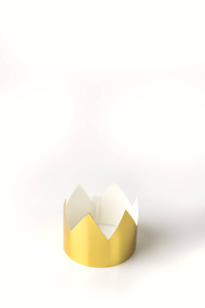 Cardboard golden crowns lying on a white table. Minimalistic style. Place for text. Copyspace. stock photo