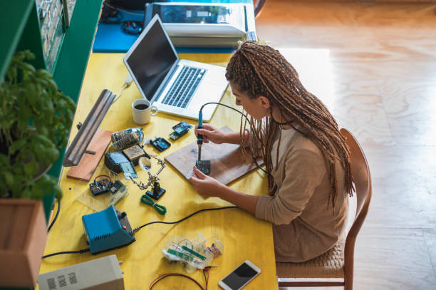 istock Woman electronics engineer is soldering circuit  board in her workshop stock photo 1264132541