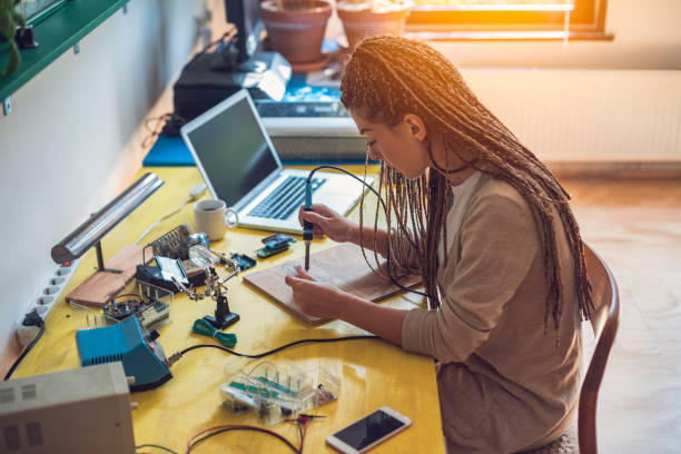istock Woman electronics engineer is soldering circuit  board in her workshop stock photo 1264132831