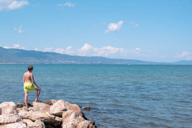 istock Teenage boy is standing on a rocks on a seashore 1264138973