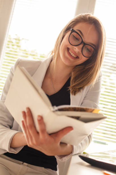 istock Smiling young female entrepreneur reading a book 1264140691