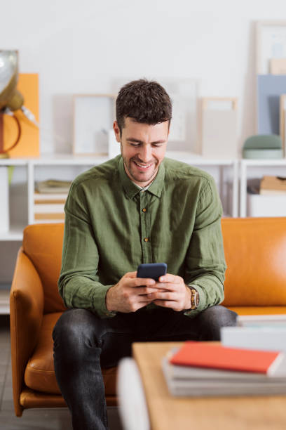 istock Smiling Modern Businessman Sitting in the Office and Using his Smartphone to Communicate Online 1264141296