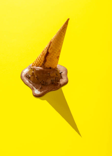 Cone ice cream melting on a yellow table. Chocolate ice cream upside down in bright light