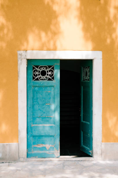 Open green double-barrelled doors with bars against the yellow wall. High quality photo
