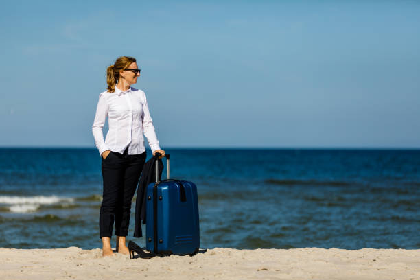 istock Businesswoman walking with suitcase at seaside 1264143277