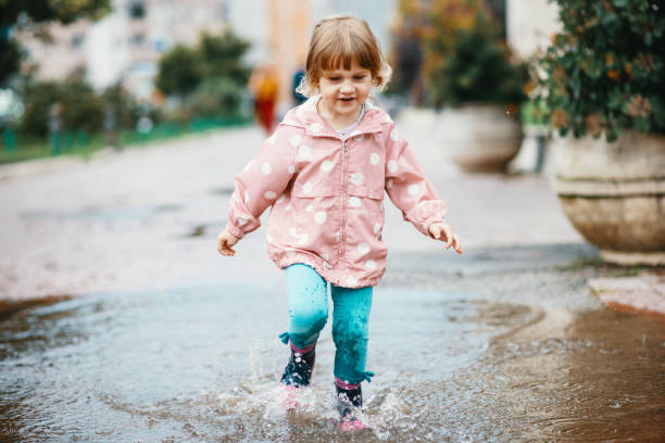 istock Three year old girl jumping in pond after rain 1264144567