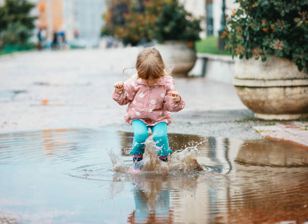 istock Three year old girl jumping in pond after rain 1264144600