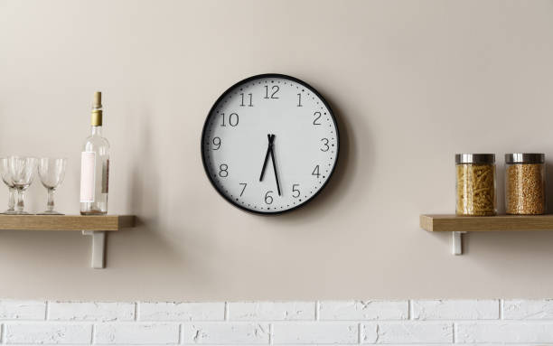 Round wall clock between wooden kitchen shelves Round wall clock between wooden kitchen shelves showing time watch timepiece photos stock pictures, royalty-free photos & images