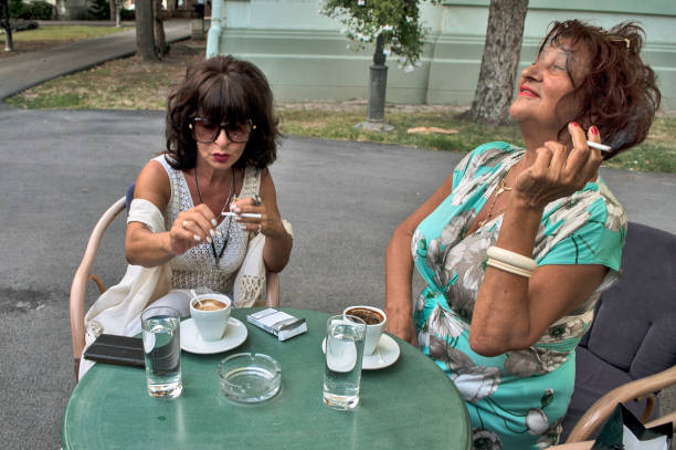 Meeting at a summer garden restaurant with two women over coffee and cigarettes. They haven't seen each other in a long time.